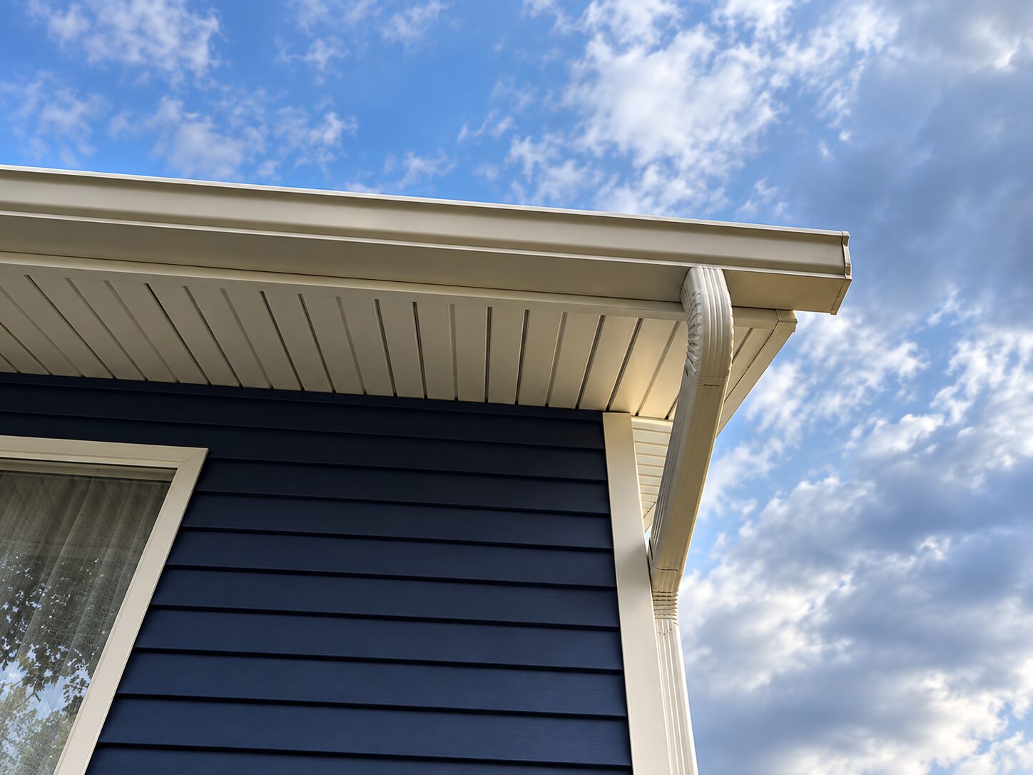 Cream gutters and soffit on a house with dark siding