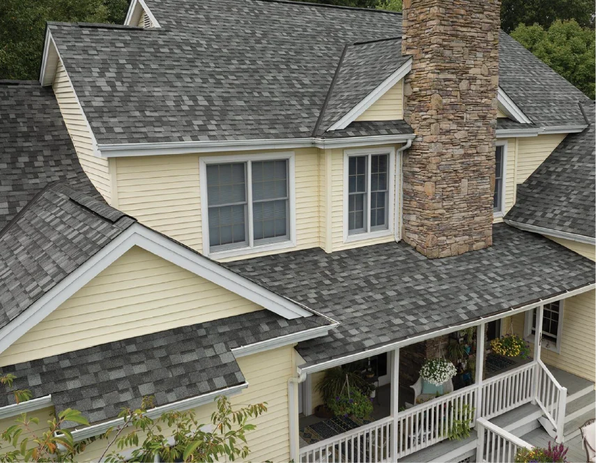 Yellow house with gray shingle roof, chimney, and white porch.