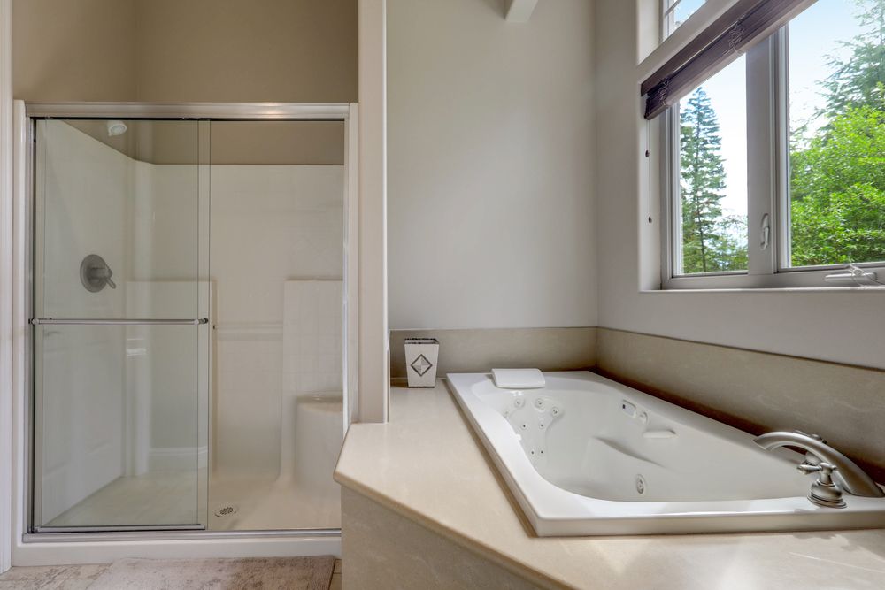 Modern bathroom with a glass shower, a rectangular tub, and a window.