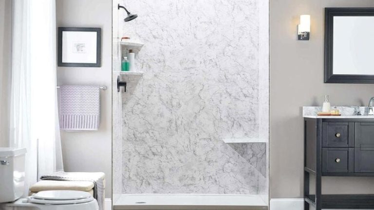 Bathroom with a marble-patterned shower, storage shelves, and a built-in seat. A framed picture and towel rack are to the left.