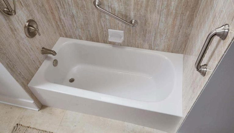 White bathtub with grab bars in a bathroom with light-colored patterned walls.