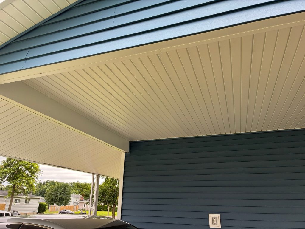 New white soffit on the underside of a carport roof beside blue siding on a Florissant, MO home.