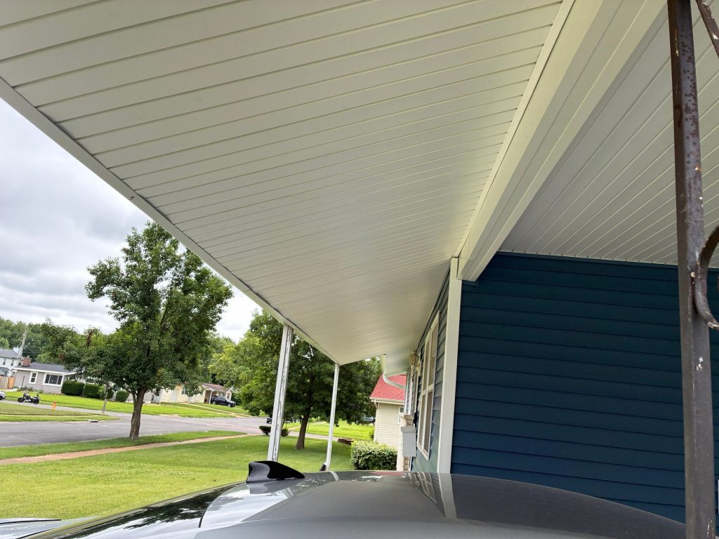 A long run of new white porch soffit beside blue siding on a Florissant, MO home.