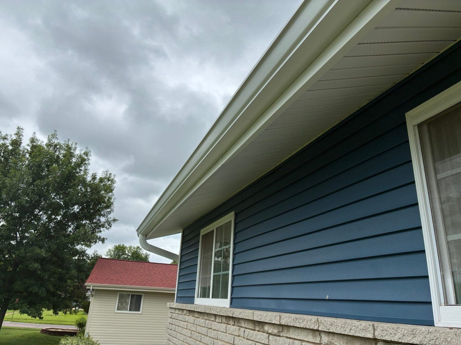 White gutter, fascia and soffit along the eave of a blue-sided home in Florissant, MO.