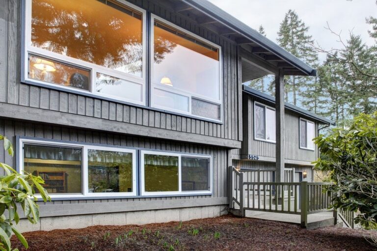 A gray board-and-batten home in Peoria with large white energy-efficient picture windows on both floors.